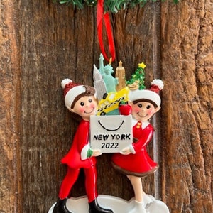 New York Skating Couple Shopping Holding Bag Filled With NYC Landmark Ornament
