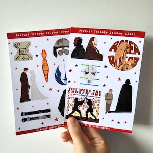 May include: Two sticker sheets with a red border featuring Star Wars prequel trilogy characters and symbols. The sheets include images of Darth Maul, Anakin, Obi-Wan, and other characters. Text on the sheets reads "Prequel Trilogy Sticker Sheet".