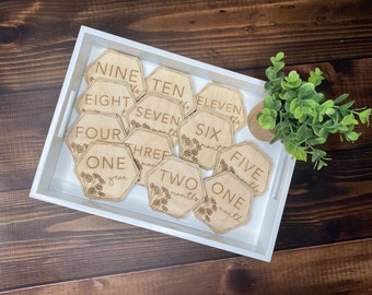 May include: Wooden hexagonal baby milestone markers with floral designs and numbers one through eleven, and the words "one year" and "one month".