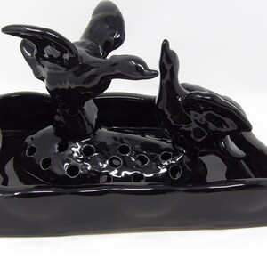May include: Black ceramic bird figurine with a small bird perched on its back. The birds are sitting in a black ceramic tray with holes in the bottom.