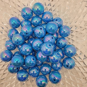 May include: A bowl filled with iridescent blue beads. The beads are round and have a smooth, glossy finish.