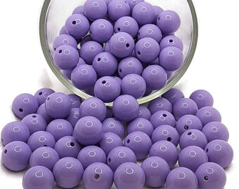 May include: A large bowl filled with purple beads. The beads are round and have a glossy finish. The beads are spilling out of the bowl onto a white surface.