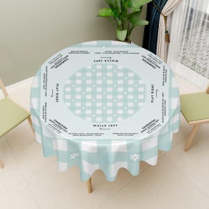 May include: A round tablecloth with a blue and white checkered pattern and small white flowers. The center of the tablecloth has a circle with a checkered pattern and the words "WALLS LEFT" and "PLAY RIGHT" written around it.