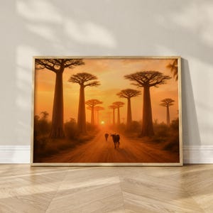 Könnte beinhalten: Gerahmter Druck einer Sonnenuntergangsszene mit einer Straße, die von hohen Baobab-Bäumen gesäumt ist. Der Himmel ist warm orange und gelb, mit der untergehenden Sonne in der Ferne. Zwei dunkle Figuren, möglicherweise Rinder, gehen die Straße entlang.