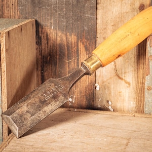 May include: A vintage wood chisel with a light-coloured wooden handle and a dark, weathered metal blade. The metal blade features the stamped text I. SORBY CAST STEEL, while the wooden handle displays the faint, stamped name A. FOSTER.