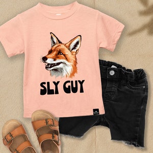 May include: A peach-colored t-shirt with a graphic of a fox and the text "SLY GUY".