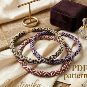 May include: Three beaded necklaces in black, red, green, and purple geometric patterns. The necklaces are displayed on a cream-colored surface with a gold jewelry stand, a velvet box, and a perfume bottle. The text "PDF pattern" is visible.