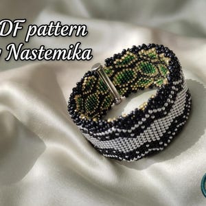 May include: A beaded bracelet featuring a geometric pattern in black, silver, and green, secured with a silver-toned metal bar clasp. The text 'PDF pattern by Nastemika' is visible in the upper left corner, and a circular logo is in the bottom right.
