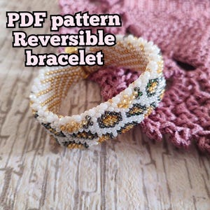 Op de afbeelding: Een omkeerbare armband van kralen met een luipaardprint. De armband heeft witte, gouden en zwarte kralen. De tekst "PDF pattern Reversible bracelet" staat in de afbeelding. De armband ligt op een lichtgekleurd houten oppervlak.