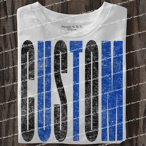 May include: White t-shirt with the word "CUSTOM" printed in large, distressed black and blue letters. The shirt has a crew neck and is folded neatly. The text "Patterns 4u by Fe Etsy.com" is printed on the collar.