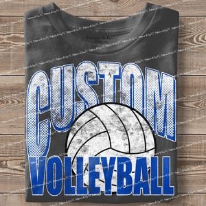 May include: A charcoal gray t-shirt featuring the words "CUSTOM VOLLEYBALL" in a distressed, blue and white design. A volleyball graphic is centered below the word "CUSTOM". The shirt is folded on a wooden surface.