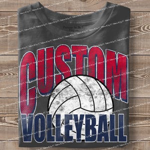 May include: Dark gray t-shirt with the words "CUSTOM VOLLEYBALL" in red and blue block letters. A white and gray volleyball graphic is centered below the word "CUSTOM". The shirt is folded on a wooden surface.