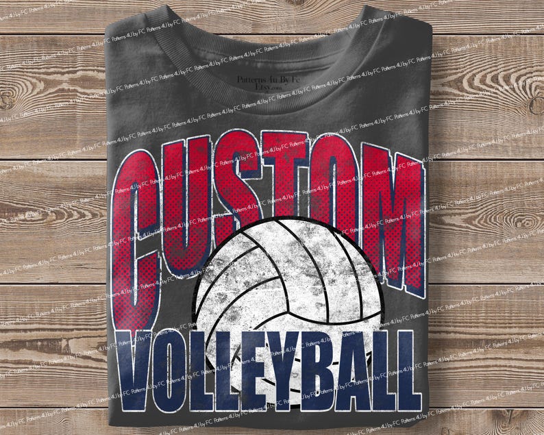 May include: Dark gray t-shirt with the words "CUSTOM VOLLEYBALL" in red and blue block letters. A white and gray volleyball graphic is centered below the word "CUSTOM". The shirt is folded on a wooden surface.