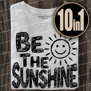 May include: White t-shirt with the phrase "BE THE SUNSHINE" in black, handwritten-style lettering. A smiling sun graphic is next to the text. A circular graphic with "10 in 1" is in the upper right corner.