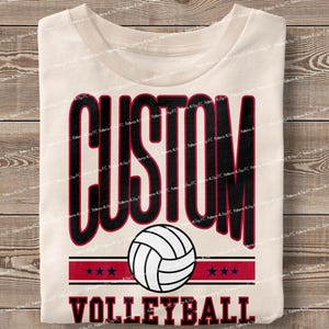 May include: A white t-shirt with the text "CUSTOM VOLLEYBALL" in black and red lettering. A black and white volleyball graphic is centred above the text.