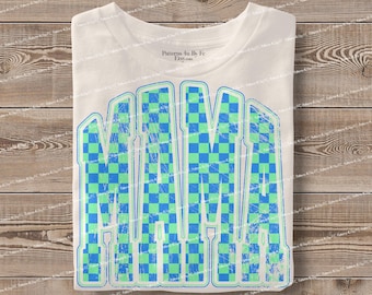 May include: White t-shirt with the word "MAMA" in large, distressed, blue and green checkered letters. The shirt is laid flat on a wooden surface. The text "Patterns 4u by Fe Etsy.com" is in the upper right corner.