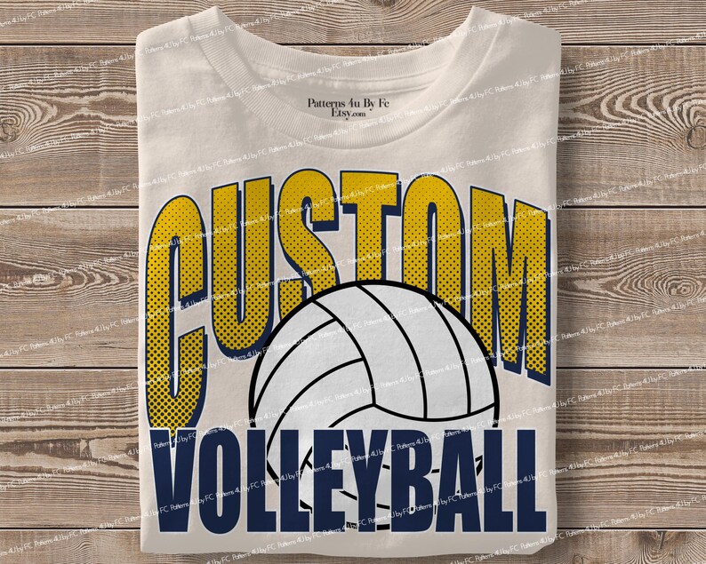 May include: Cream-colored t-shirt with the words "CUSTOM VOLLEYBALL" in a bold, two-tone design. The word "CUSTOM" is in yellow with a dotted pattern, and "VOLLEYBALL" is in navy blue. A white volleyball graphic is centered.