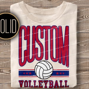 May include: A white t-shirt with a red and blue design that says "CUSTOM VOLLEYBALL" with a volleyball graphic in the centre.