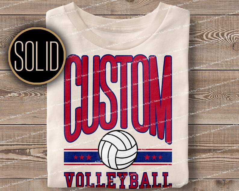 May include: A white t-shirt with a red and blue design that says "CUSTOM VOLLEYBALL" with a volleyball graphic in the centre.