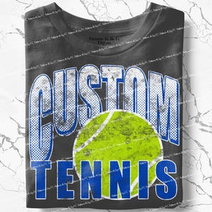 Puede incluir: Camiseta gris oscuro con las palabras "CUSTOM TENNIS" en una fuente desgastada blanca y azul. Un gr&aacute;fico de pelota de tenis en verde y amarillo est&aacute; centrado debajo de la palabra "CUSTOM".