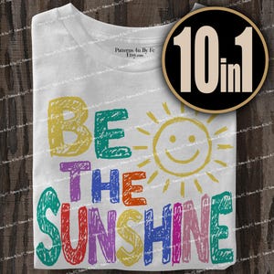 May include: White t-shirt with the phrase "BE THE SUNSHINE" in colorful, hand-drawn letters. A smiling sun graphic is next to the text. A circular graphic with the text "10 in 1" is in the upper right corner.