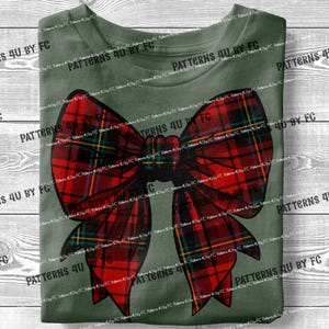 May include: A green t-shirt with a red and black plaid bow on the front. The bow is tied in a knot and has a large, flowing loop.