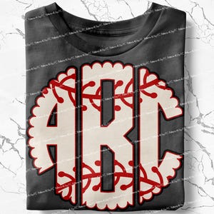 May include: A gray t-shirt with a white and red monogram design. The monogram is in the shape of a baseball with a scalloped edge.
