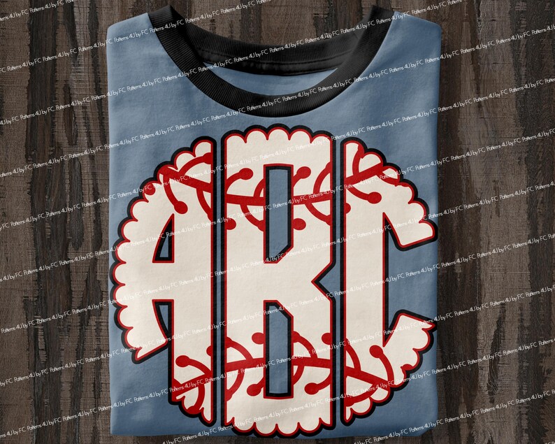 May include: A light blue t-shirt with a white and red monogram design. The monogram is in the shape of a baseball with a scalloped edge.