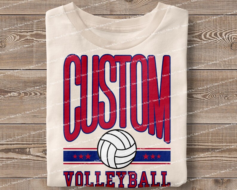 May include: A white t-shirt with a red and blue design that says "CUSTOM VOLLEYBALL" with a volleyball graphic in the centre.