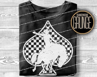 Może przedstawiać: Czarny t-shirt z białym nadrukiem przedstawiającym kowboja na koniu w kształcie pika. Pik ma wzór w szachownicę. Koszulka ma postarzany, vintage wygląd.