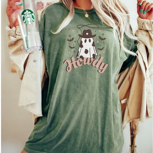 May include: A green t-shirt with a white ghost wearing a cowboy hat and the text "Howdy". The ghost has black polka dots and is surrounded by bats and stars.
