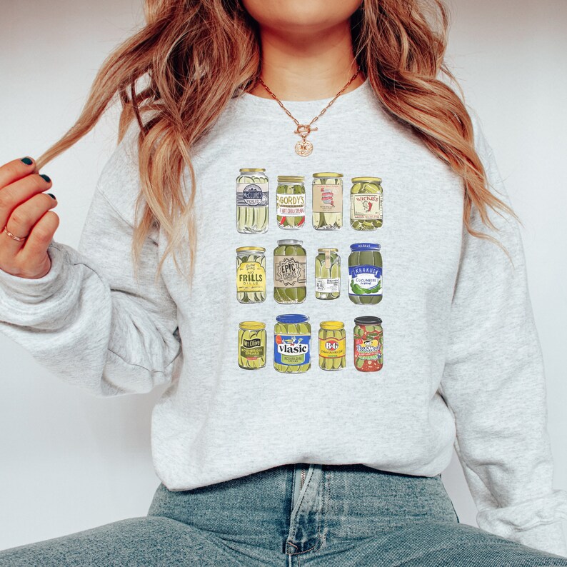 Op de afbeelding: Een grijs sweatshirt met een grafische print van verschillende augurkenpotten. De potten zijn in een rasterpatroon gerangschikt en bevatten verschillende augurkenmerken, waaronder Vlasic, Gordy's en B&G.