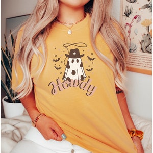 May include: A yellow t-shirt with a ghost wearing a cowboy hat and the word "Howdy" printed on it.