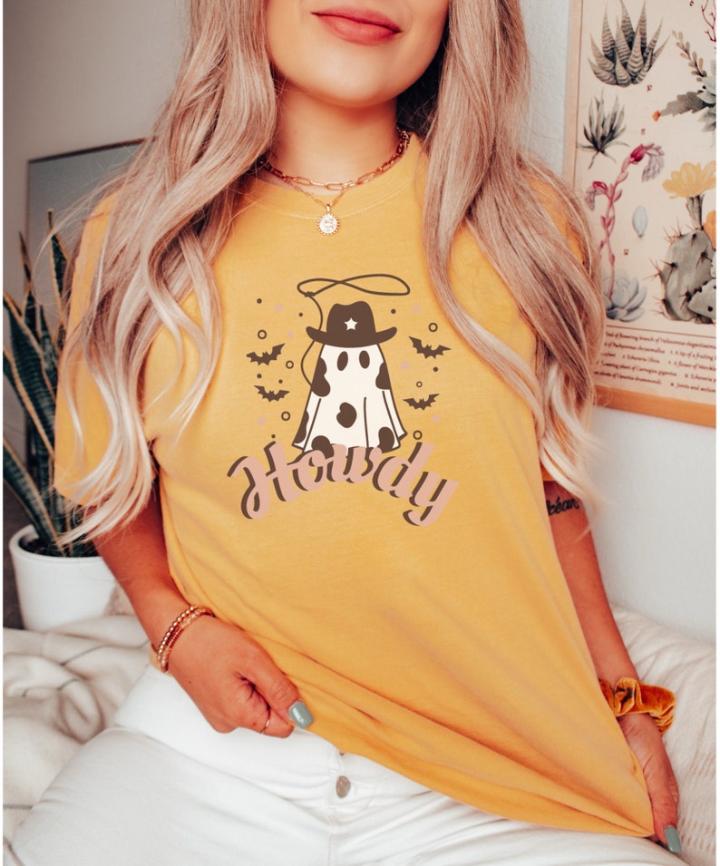 May include: A yellow t-shirt with a ghost wearing a cowboy hat and the word "Howdy" printed on it.