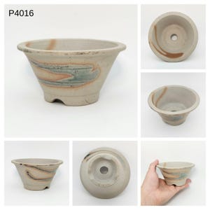 May include: A beige ceramic bonsai pot with a flared shape and three small feet. The pot features a decorative design in shades of blue, orange, and brown. The text "P4016" is visible in the upper left corner.
