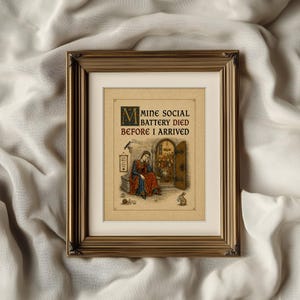May include: A framed print featuring a medieval-style illustration of a person sitting outside a doorway with the text MINE SOCIAL BATTERY DIED BEFORE I ARRIVED. The artwork includes a bird, a snail, and a rabbit, all set within a gold frame.