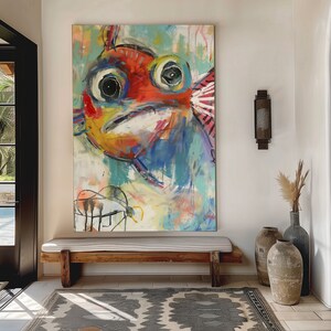 May include: A colorful abstract painting of a fish with large eyes and a bright red, yellow, and blue body. The painting is hanging on a white wall above a wooden bench.
