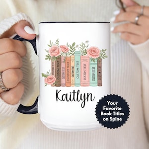 May include: White ceramic mug with a black interior and handle, featuring a floral design with pink roses and a stack of books. The mug has the name "Kaitlyn" and the text "Your Favorite Book Titles on Spine".