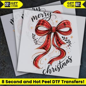 May include: A white DTF transfer sheet featuring a large red plaid bow with gold trim, surrounded by small gold stars and black leafy sprigs. The text "merry christmas" is written in black cursive script above and below the central bow design.