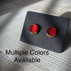 May include: A pair of small, round, red stud earrings with gold settings. Multiple Colors Available.