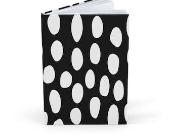 Puede incluir: Un cuaderno negro con un patrón de lunares blancos.