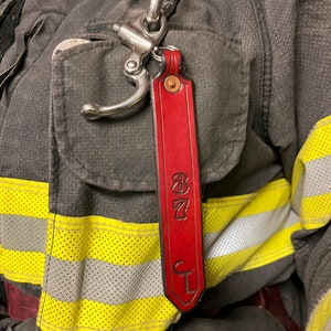 May include: Red leather keychain with a metal clip and the text "87 CL" embossed on it.