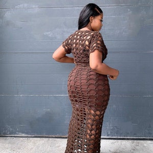 May include: A brown crochet maxi dress with a  pattern of open squares and circles. The dress has a short sleeve and a fitted bodice.