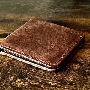 Peut inclure: Un portefeuille en cuir marron avec un bord cousu.