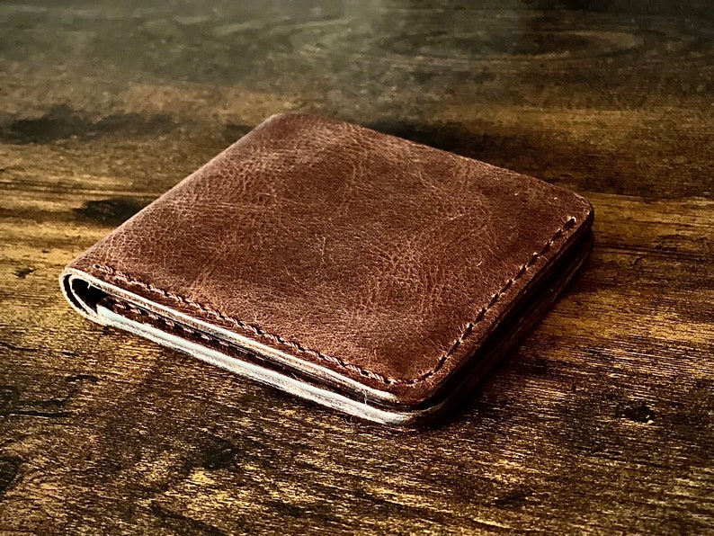 Peut inclure: Un portefeuille en cuir marron avec un bord cousu.