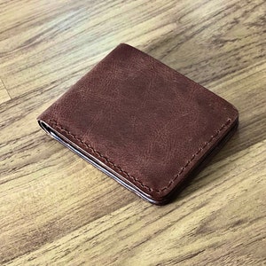 Peut inclure: Un portefeuille en cuir marron avec un bord cousu.