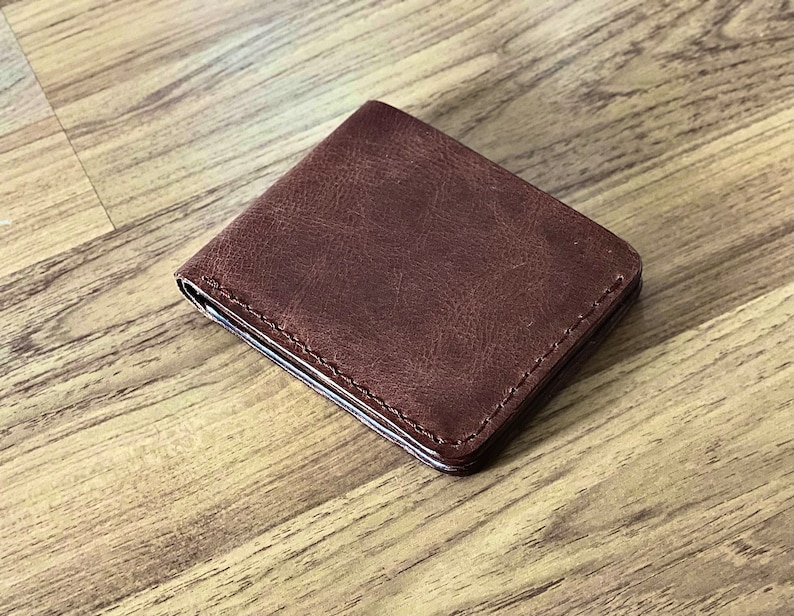 Peut inclure: Un portefeuille en cuir marron avec un bord cousu.