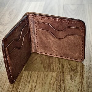 Peut inclure: Un portefeuille en cuir marron avec plusieurs fentes pour cartes et un design rabattable.
