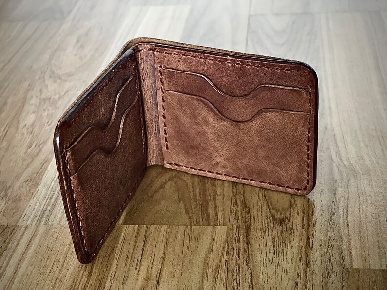 Peut inclure: Un portefeuille en cuir marron avec plusieurs fentes pour cartes et un design rabattable.