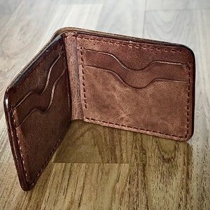 Peut inclure: Un portefeuille en cuir marron avec plusieurs fentes pour cartes et un design rabattable.